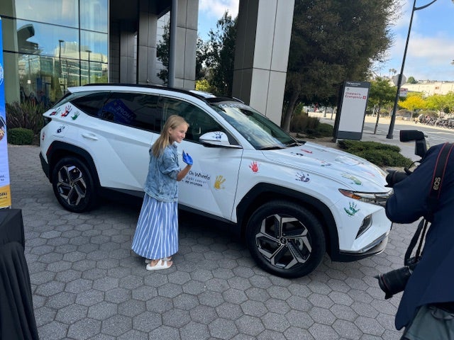 group of people with big checks in front of car